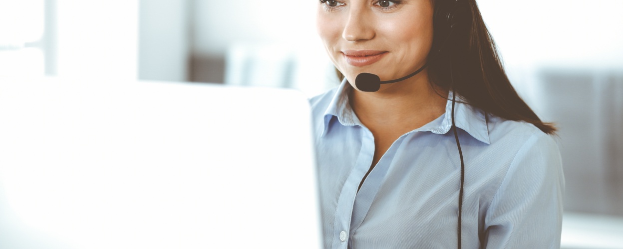 Frau sitzt am Schreibtisch und telefoniert mit einem Headset