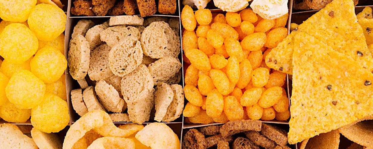 A wide variety of savory snacks in a cardboard box with different compartments